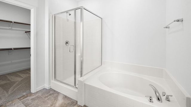 bathroom with a garden tub, a stall shower, and a walk in closet