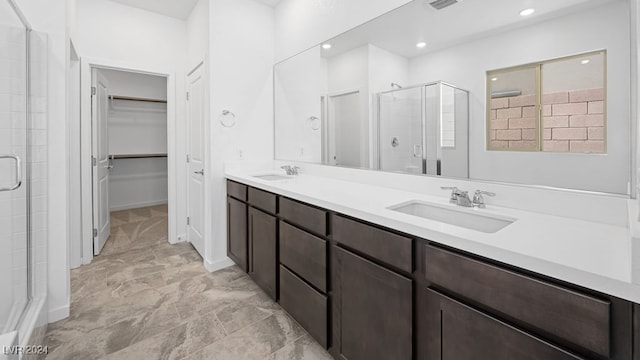 full bath featuring double vanity, a sink, a shower stall, and a spacious closet