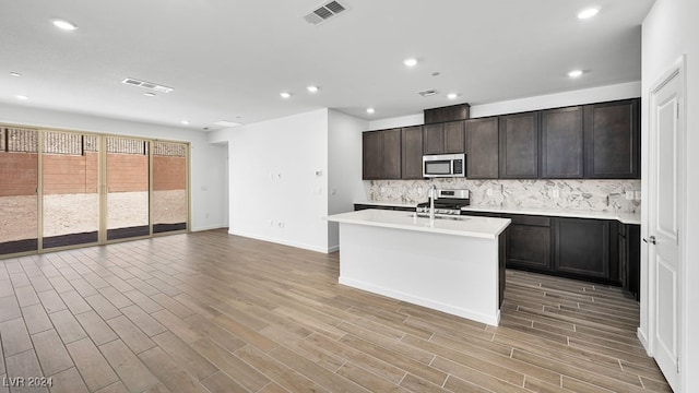 kitchen with stainless steel appliances, visible vents, backsplash, light countertops, and open floor plan