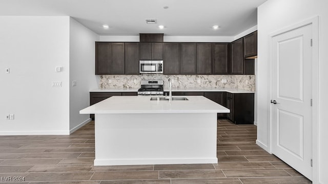 kitchen featuring a sink, wood tiled floor, dark brown cabinetry, visible vents, and appliances with stainless steel finishes