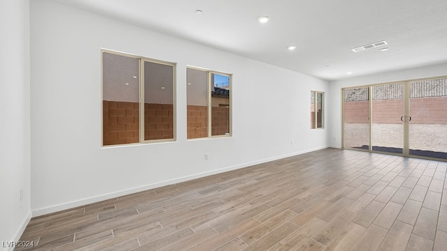 empty room featuring recessed lighting, visible vents, wood finished floors, and baseboards