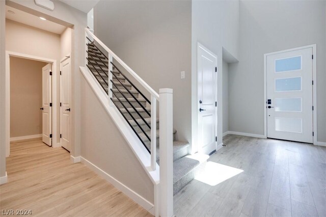 foyer entrance with light wood-type flooring and a towering ceiling