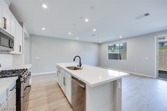 kitchen with sink, light hardwood / wood-style flooring, stainless steel appliances, and a kitchen island with sink