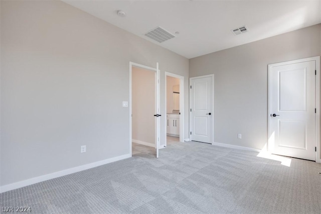 unfurnished bedroom featuring ensuite bathroom and light carpet