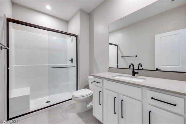 bathroom with tile patterned flooring, walk in shower, toilet, and vanity