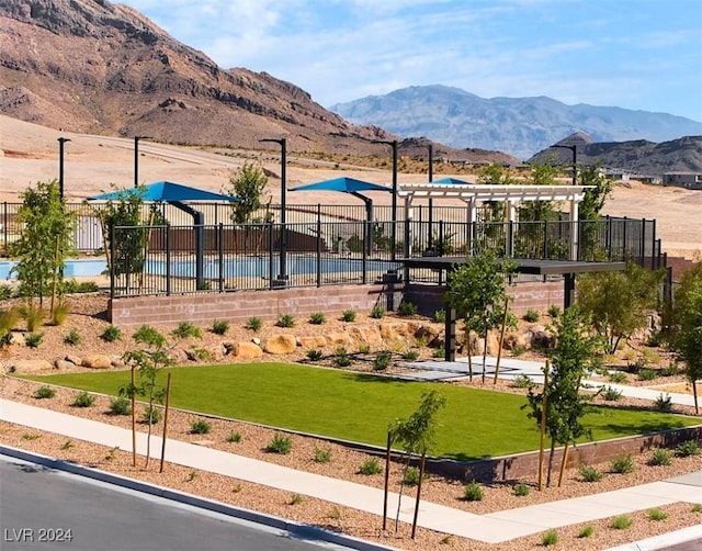 view of property's community with a swimming pool, a yard, a mountain view, and a pergola