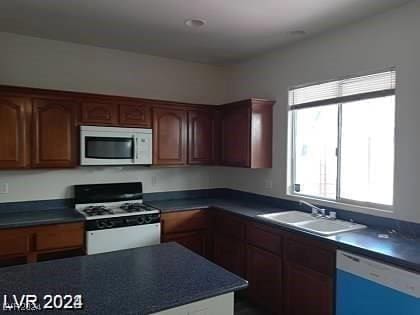 4085 Oliver Sagebrush Dr, Las Vegas, NV 89122 - kitchen with white appliances, dark countertops, and a sink