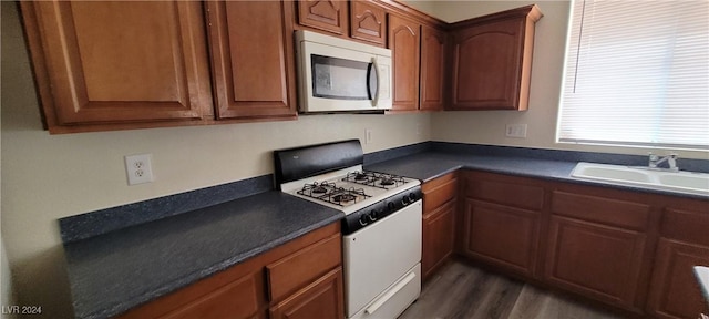 4085 Oliver Sagebrush Dr, Las Vegas, NV 89122 - kitchen with white gas stove, a sink, dark countertops, dark wood-style floors, and brown cabinets