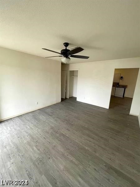 spare room with a textured ceiling, ceiling fan, and dark hardwood / wood-style floors