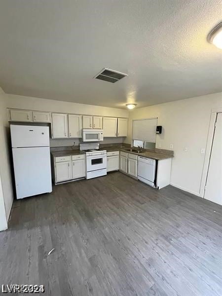 kitchen with a textured ceiling, dark hardwood / wood-style floors, white appliances, and white cabinets