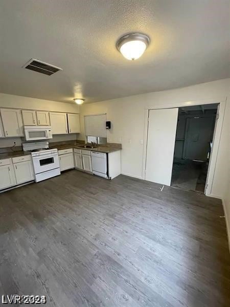 kitchen with sink, dark hardwood / wood-style flooring, white cabinetry, and white appliances