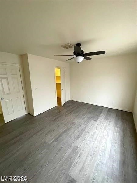 unfurnished bedroom with a spacious closet, a closet, ceiling fan, and dark hardwood / wood-style floors