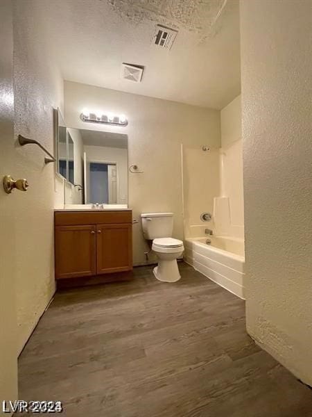 full bathroom featuring a textured ceiling, toilet, vanity,  shower combination, and hardwood / wood-style flooring