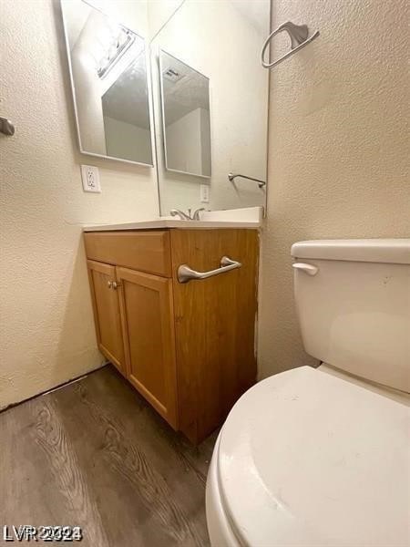 bathroom with vanity, toilet, and hardwood / wood-style floors