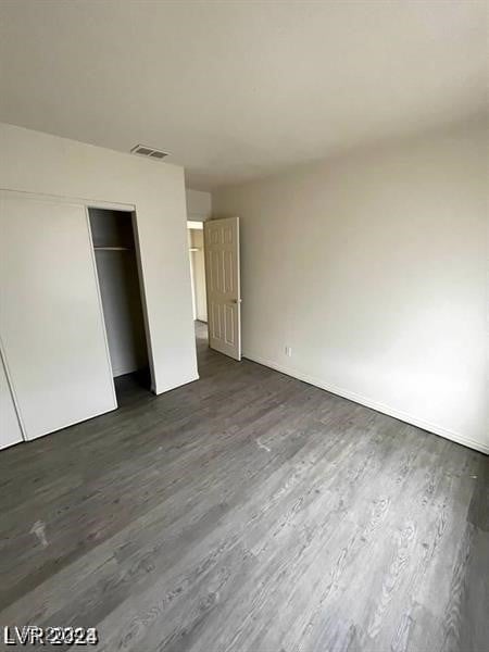 unfurnished bedroom featuring dark hardwood / wood-style floors and a closet