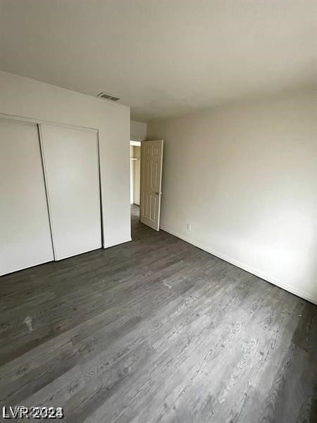 unfurnished bedroom with dark hardwood / wood-style floors and a closet