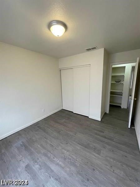 unfurnished bedroom featuring dark wood-type flooring and a closet