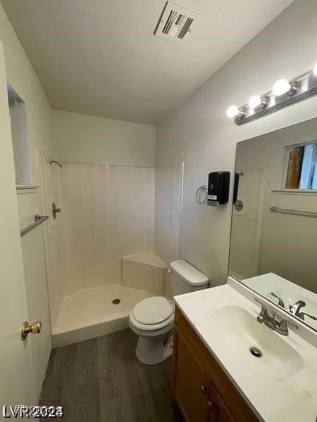 bathroom featuring walk in shower, wood-type flooring, toilet, and vanity