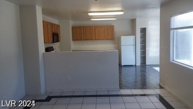 kitchen featuring white fridge, a healthy amount of sunlight, and light tile patterned floors