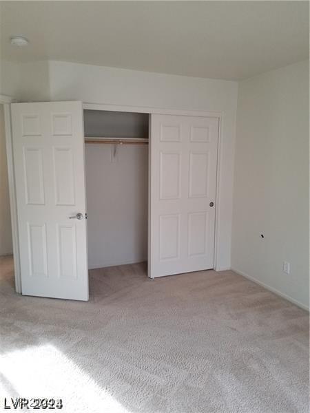 unfurnished bedroom featuring light colored carpet and a closet