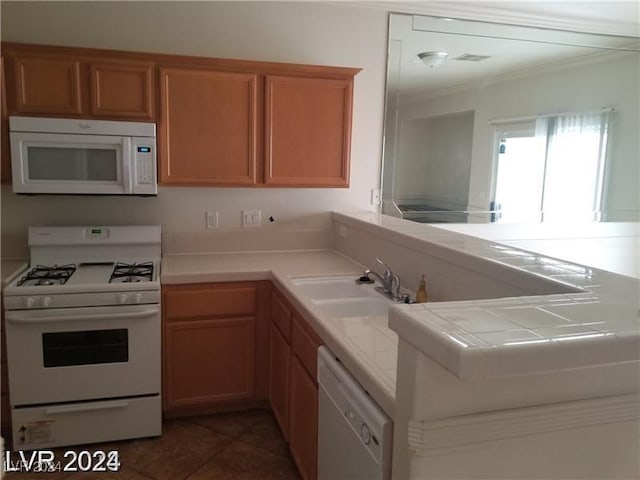 kitchen featuring sink, white appliances, dark tile patterned flooring, tile countertops, and kitchen peninsula