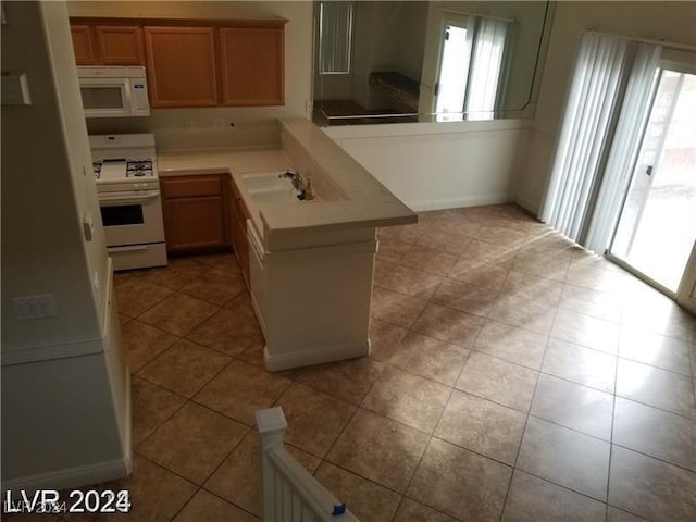 kitchen with sink, light tile patterned floors, white appliances, and kitchen peninsula