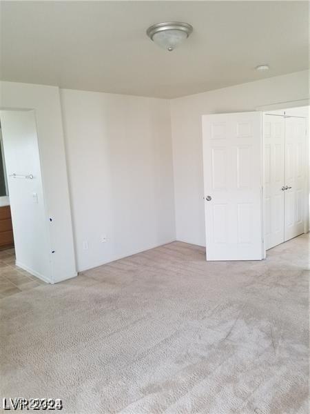 unfurnished bedroom with light colored carpet and a closet