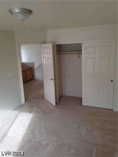 unfurnished bedroom with light colored carpet and a closet