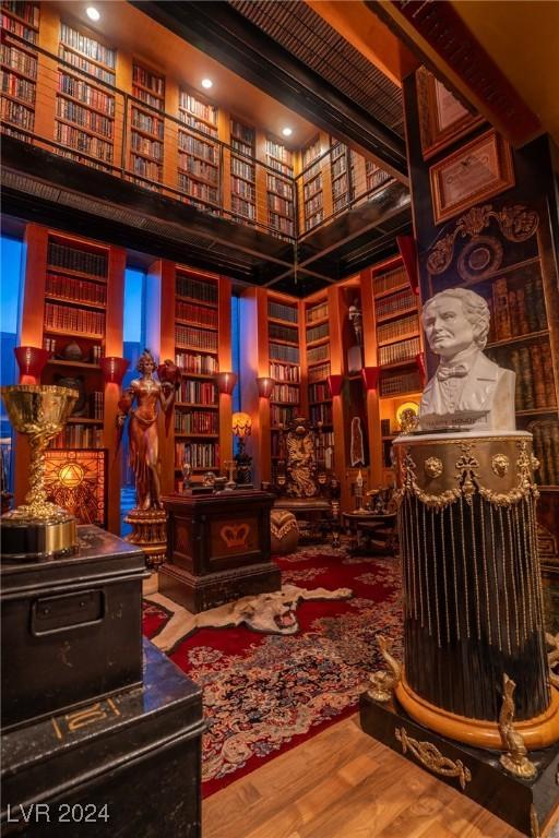 sitting room featuring wall of books and wood finished floors