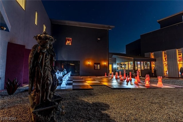 back of house at night with a patio and stucco siding