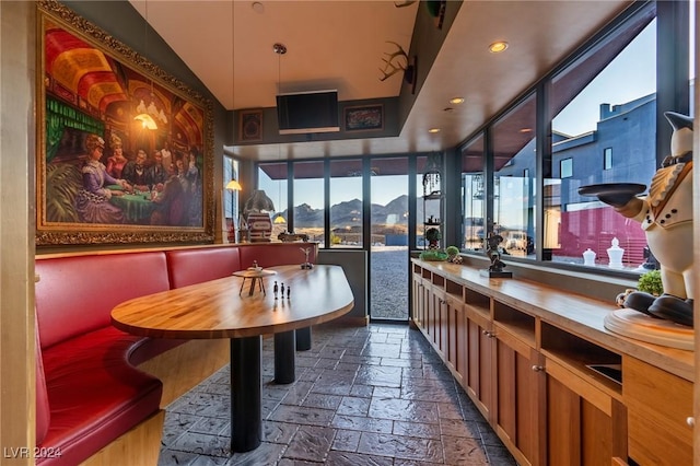 interior space featuring lofted ceiling, decorative light fixtures, and stone tile floors