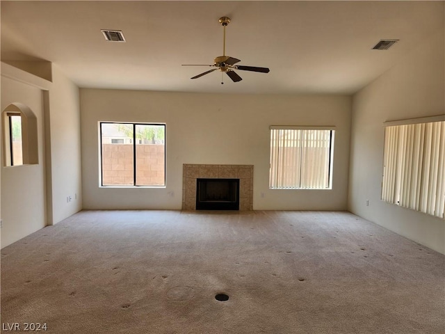 unfurnished living room with ceiling fan, light colored carpet, and a tile fireplace