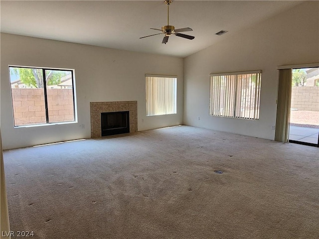 unfurnished living room with a tiled fireplace, ceiling fan, light carpet, and high vaulted ceiling