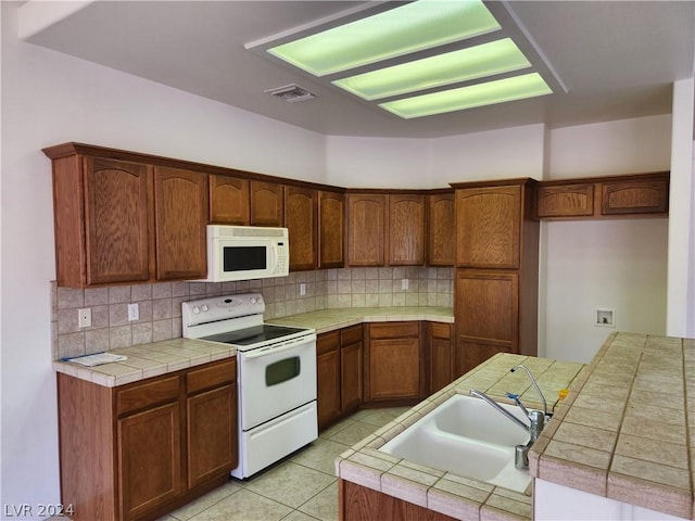 kitchen featuring tasteful backsplash, sink, white appliances, and tile counters