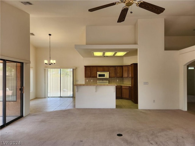 kitchen featuring hanging light fixtures, a kitchen breakfast bar, a high ceiling, tasteful backsplash, and light carpet