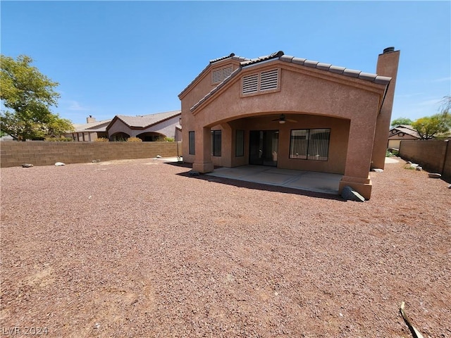 rear view of property with ceiling fan and a patio area