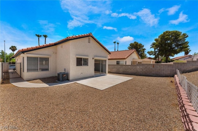 back of property with central AC and a patio