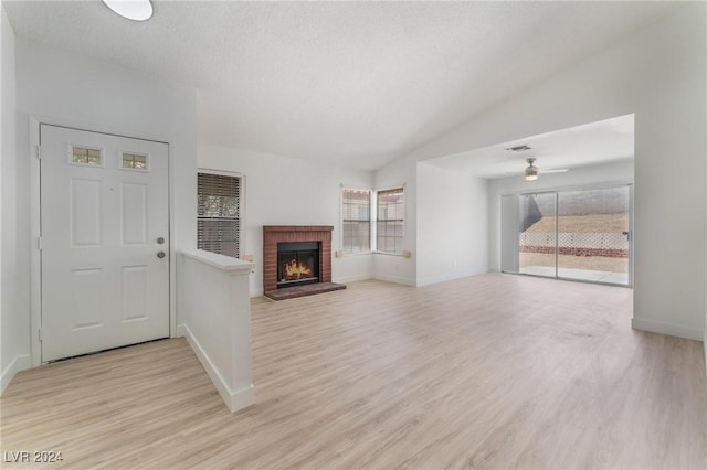 unfurnished living room with ceiling fan, a healthy amount of sunlight, a fireplace, and light hardwood / wood-style flooring