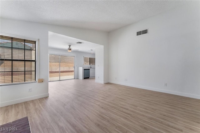 unfurnished living room with lofted ceiling, ceiling fan, a textured ceiling, and light wood-type flooring