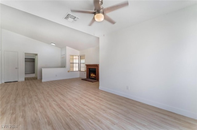 unfurnished living room featuring ceiling fan, a brick fireplace, vaulted ceiling, and light hardwood / wood-style flooring