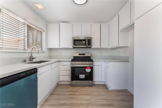 kitchen featuring white cabinetry, stainless steel appliances, sink, and light hardwood / wood-style flooring