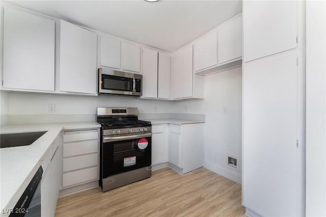 kitchen featuring appliances with stainless steel finishes, sink, light hardwood / wood-style floors, and white cabinets