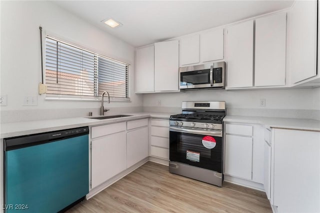 kitchen featuring sink, light wood-type flooring, white cabinets, and appliances with stainless steel finishes