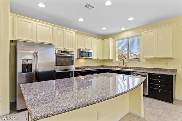 kitchen with stainless steel appliances, dark stone countertops, visible vents, and a center island