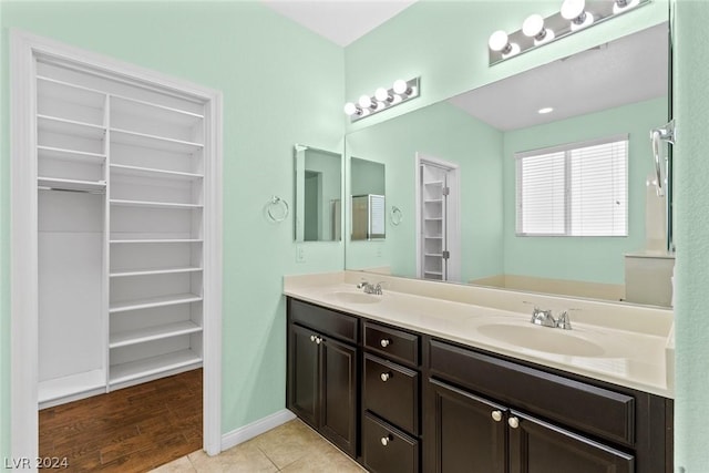 full bathroom featuring tile patterned flooring, a sink, a spacious closet, and double vanity