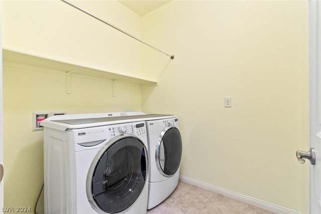 washroom featuring laundry area, washer and clothes dryer, baseboards, and light tile patterned floors