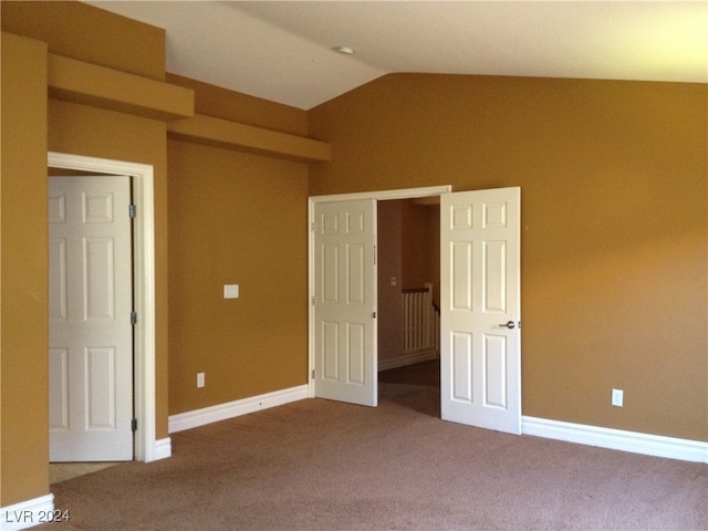 unfurnished bedroom with carpet flooring and lofted ceiling