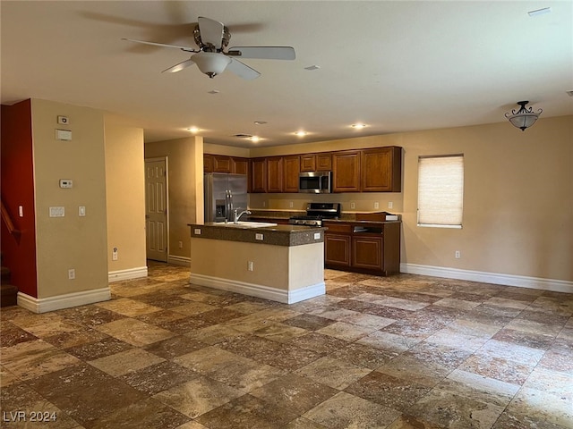 kitchen featuring ceiling fan, sink, stainless steel appliances, and an island with sink