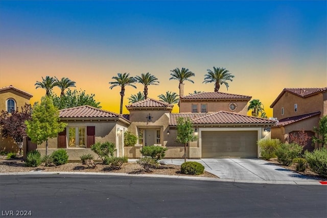 mediterranean / spanish-style house featuring a tiled roof, stucco siding, driveway, and an attached garage