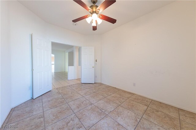 tiled empty room featuring ceiling fan